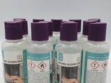 quatre flacons de gel hydroalcoolique posés sur une surface blanche