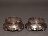 two silver pots sitting on a table next to each other
