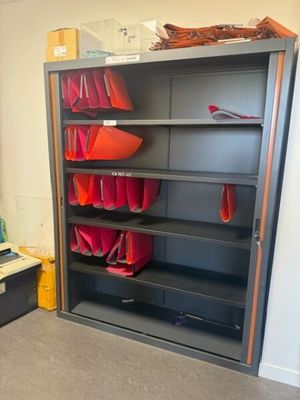 une bibliothèque sur laquelle sont posés plusieurs sacs rouges