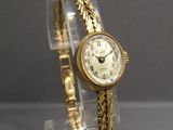 une montre-bracelet en or posée sur un présentoir transparent