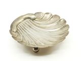 un objet argenté en forme de coquille posé sur une surface blanche