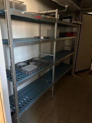 a metal shelf in a kitchen with dishes and pans on it