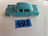 une petite voiture bleue posée à côté d'une feuille de papier