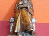statue d'un vieil homme assis sur un banc en train de lire un livre