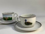 two cups and saucers with a picture of a duck on them