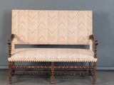 un vieux banc en bois dont l'assise est recouverte d'un tissu à motifs beiges et blancs