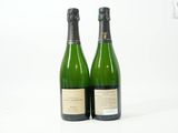 deux bouteilles de vin posées l'une à côté de l'autre sur une surface blanche