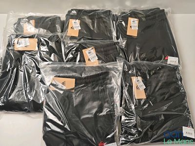 de nombreux sacs contenant des vêtements noirs posés sur une table blanche