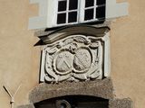 a clock on the side of a building with a window above it