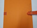 a close up of a piece of orange paper with a buckle on it