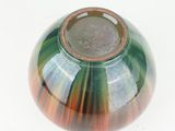 a green and orange vase with a brown rim
