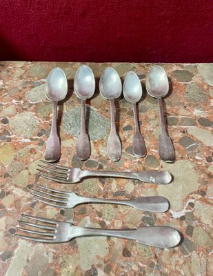 cinq cuillères en argent et six cuillères en argent posées sur une table en marbre