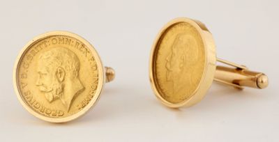 un gros plan sur une paire de boutons de manchette en or ornés d'une pièce de monnaie