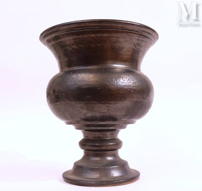 un vase en métal posé sur une surface blanche