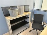 a desk with a chair and a shelf with bins on it