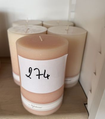 une bougie posée sur une étagère à côté de quelques rouleaux de papier toilette