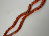 un gros plan d'un collier de perles orange posé sur une surface blanche