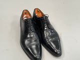 men ' s black dress shoes on a white surface