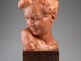 a bronze bust of a man with his head resting on a wooden block