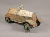 Une petite voiture ancienne est posée sur une surface grise