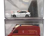 a red toy ambulance and a white car in a clear box