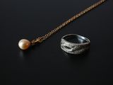 an image of a ring and a pearl on a black surface