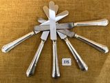cinq couteaux et un porte-couteaux posés sur une table
