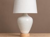 une lampe de table blanche posée sur une table en bois, près d'un mur marron