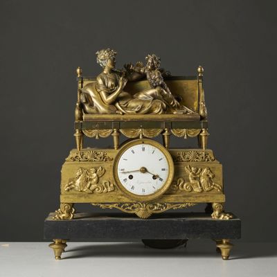 a gold clock with a statue of a man and a woman on it