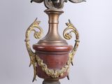 a large vase on a pedestal with a chandelier in the background