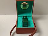 un petit flacon de parfum dans une boîte posée sur une table