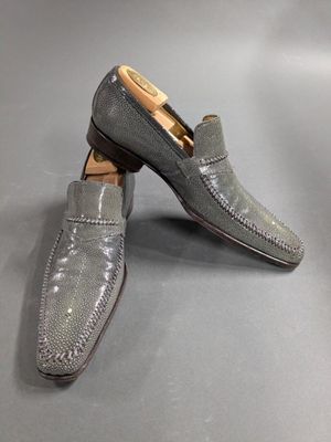 a pair of gray shoes with a brown sole on a gray surface