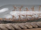 a glass bottle with a ship in it on a rope
