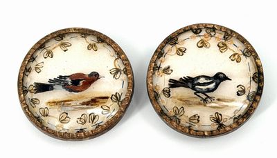 une paire de petits oiseaux en céramique posés sur une surface blanche
