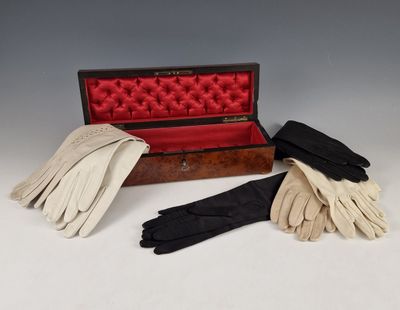 trois paires de gants en cuir dans un étui posé sur une surface blanche