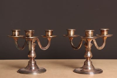 une paire de chandeliers anciens en métal argenté posés sur une table en bois
