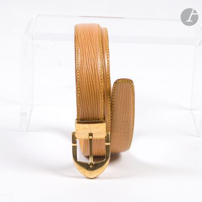 ceinture en cuir beige avec boucle dorée, présentée dans une vitrine en acrylique transparent