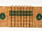 six old books are lined up in a row on a white surface