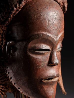 un gros plan d'un masque en bois orné de dreadlocks