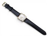 a close up of a watch on a white surface with a black strap