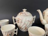 five cups and a teapot sitting on a table