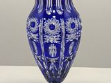 a blue vase sitting on a table with a white wall in the background