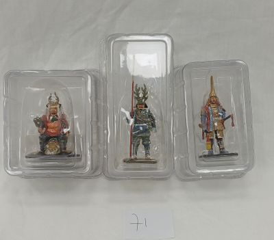 three miniature figurines of knights in plastic containers on a white surface