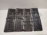 four black keyboards sitting on a white table