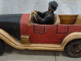 une statue représentant un homme assis dans une voiture rouge