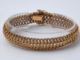 gros plan d'un bracelet en or sur une surface blanche