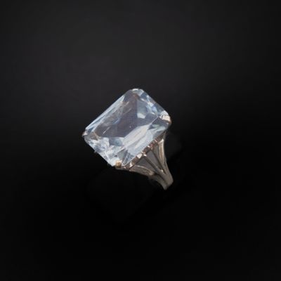 un gros plan d'une bague sertie d'une pierre transparente sur fond noir