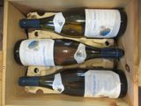 trois bouteilles de vin se trouvent dans une caisse en bois posée sur une table