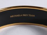 a close up of a black and gold bracelet with a name on it
