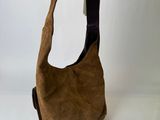 someone is holding a brown purse with a black strap